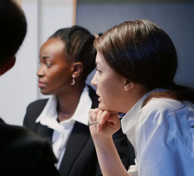Entrepreneur woman discussing financial graphs using presentation monitor working in office meeting room late at night. Diverse multi ethnic businesspeople brainstorming company ideas